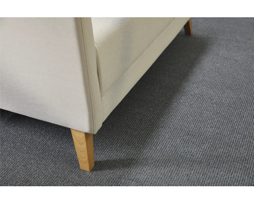 Detailansicht eines Polstersessels mit Stoffbezug und Holzfüßen auf einem Teppich