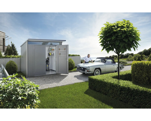 Gartenszene mit Gerätehaus, Oldtimer und Person bei der Autopflege