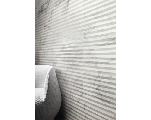 Wandgestaltung mit gestreiften Fliesen und Marmoroptik neben einem Sessel.