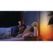 Une femme dort dans une chambre avec des lampes de chevet et un verre d''eau.