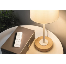 Lampe mit Holzfuß, Fernbedienung und einer dekorativen Box auf einem Tisch