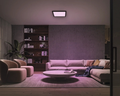 Wohnzimmer mit Sofa, Sesseln, Bücherregal und Deckenleuchte