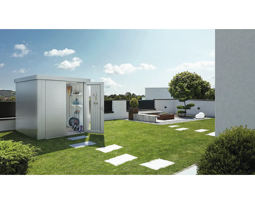 Jardin avec abri de jardin en métal, porte ouverte et outils de jardinage