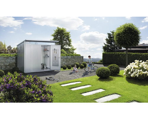 Abri de jardin en métal avec portes ouvertes, étagères et outils dans un jardin avec des enfants qui jouent