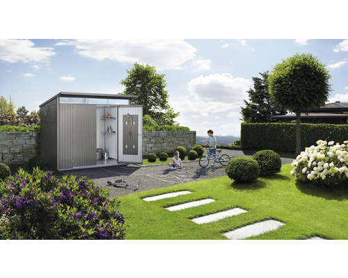 Abri de jardin métallique avec porte ouverte dans un jardin avec des enfants qui jouent.