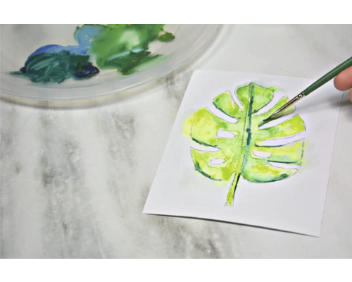 Peinture aquarelle d''une feuille de Monstera avec pinceau et palette