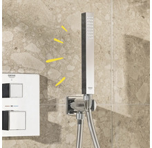 Grohe Logo, Duschkopf und Thermostatarmatur an einer gefliesten Wand
