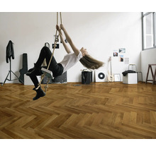 Eine Frau schwingt an einem Seil in einem Raum mit Fischgrätenparkettboden.