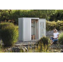Abri de jardin en métal avec étagères et outils dans le jardin avec une femme qui lit