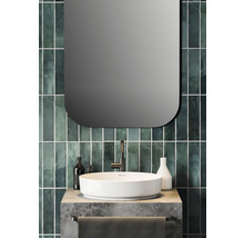 Meuble de salle de bain avec lavabo à poser, robinet et miroir devant un carrelage vert