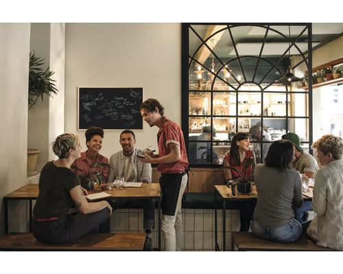 Scène dans un restaurant avec des clients attablés et un serveur prenant les commandes.