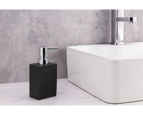 Seifenspender aus Stein neben einem Waschbecken mit Armatur