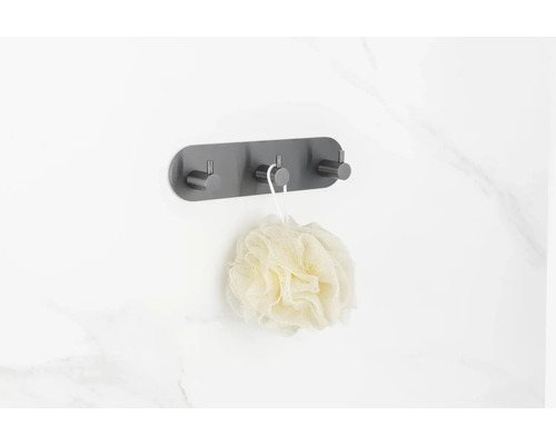 Porte-manteau mural avec trois crochets et une éponge de bain sur un mur de salle de bain