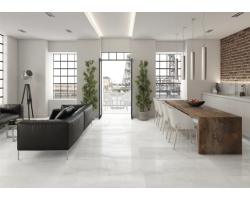 Salon lumineux avec canapé en cuir noir, table à manger et grandes fenêtres