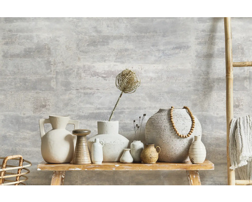 Vases décoratifs et échelle en bambou sur une table en bois devant un mur avec une structure en plâtre.