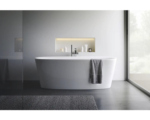 Salle de bains moderne avec baignoire îlot, robinetterie et produits de soins dans une niche