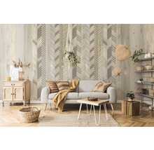 Salon avec canapé gris, table en bois, coffre en bois et papier peint mural à motif de flèches.