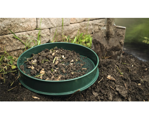 Gartensieb mit Erde und Schaufel im Garten