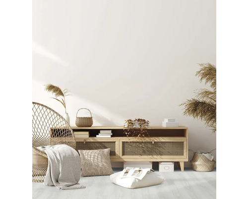 Wohnzimmer-Szene mit Rattan-Sessel, Holzkommode, Kissen und dekorativen Elementen für eine gemütliche Atmosphäre