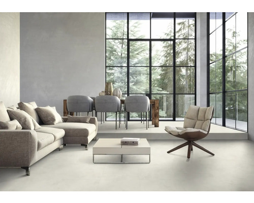 Helles Wohnzimmer mit Sofa, Sessel, Esstisch und großem Fenster mit Blick auf Bäume