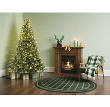 Weihnachtsszene mit geschmücktem Baum, Geschenken, Kamin und Sessel in einem gemütlichen Wohnzimmer.