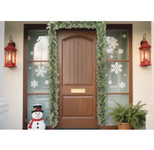 Porte d''entrée décorée avec une guirlande de sapin, des autocollants de flocons de neige et des lanternes