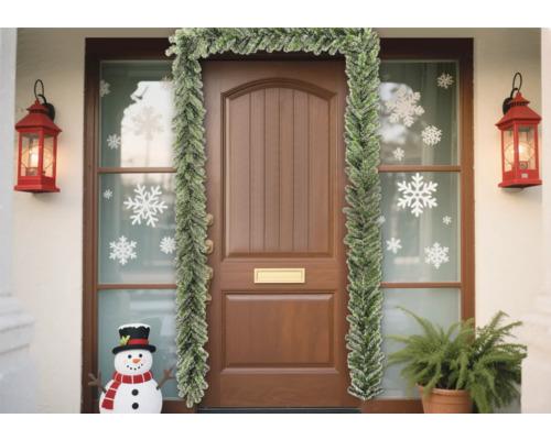 Porte d''entrée décorée avec une guirlande de sapin, des autocollants de flocons de neige et des lanternes