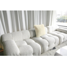 Modulares Sofa mit Kissen und Polsterstruktur vor einem Fenster mit Vorhang