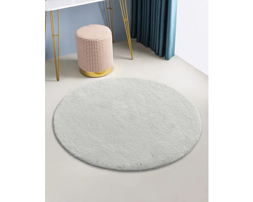 Tapis rond et clair dans une pièce avec tabouret et table.