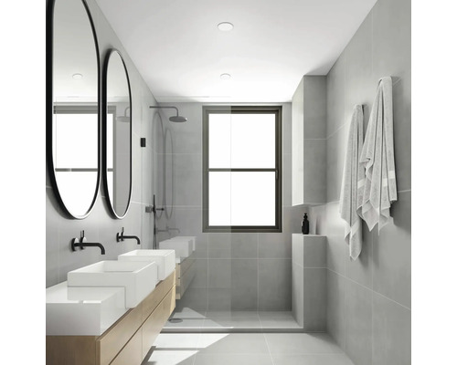 Salle de bains lumineuse avec double vasque, miroirs ovales, douche et serviettes