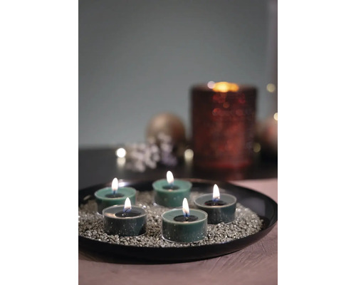 Arrangement décoratif avec des bougies chauffe-plat sur une assiette noire avec des pierres décoratives