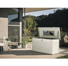 Coffre de jardin ouvert en métal sur une terrasse avec vue sur le jardin