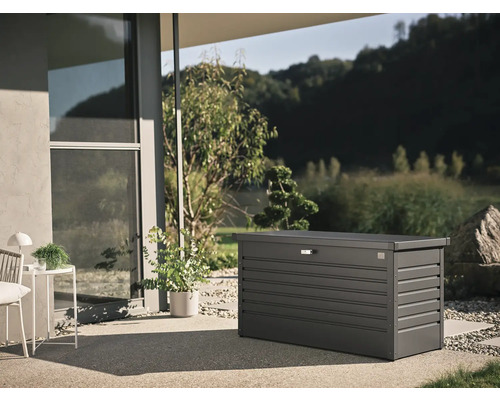 Coffre de jardin gris sur une terrasse devant une maison