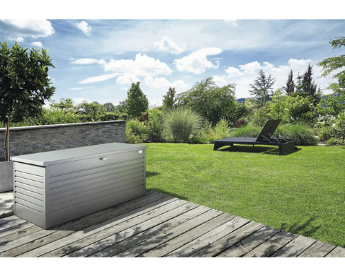 Paysage de jardin avec un coffre de rangement en métal et une chaise longue sur une pelouse