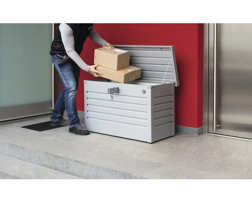 Livreur de colis déposant des colis dans une boîte à colis en métal