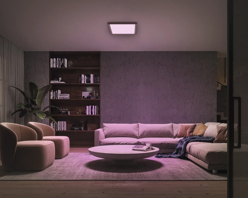 Wohnzimmer mit Sofa, Sesseln, Bücherregal und Deckenleuchte