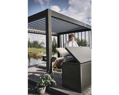 Mann verstaut Kissen in einer Aufbewahrungsbox im Aussenbereich unter einer Pergola.