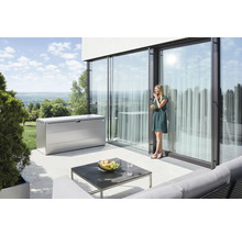 Szene mit einer Aufbewahrungsbox aus Metall auf einer Terrasse, einem Tisch und einer Frau, die Weintrauben isst
