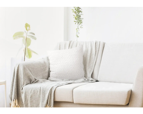 Helles Wohnzimmer mit Sofa, Kissen und Überwurfdecke