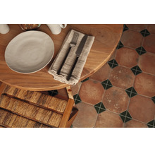 Table à manger dressée avec assiette, couverts et carrelage de sol de style vintage.