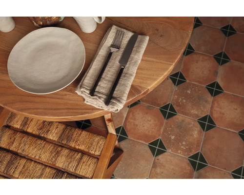 Table à manger dressée avec assiette, couverts et carrelage de sol de style vintage.