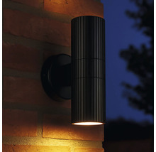 Applique murale extérieure noire avec corps de lampe nervuré sur un mur en briques