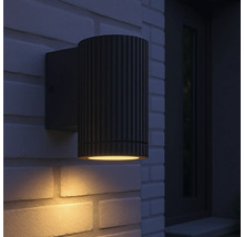 Eine schwarze Aussenwandleuchte ist an einer Backsteinmauer montiert.