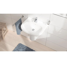 Salle de bain lumineuse avec lavabo blanc, robinet, porte-serviettes et tapis