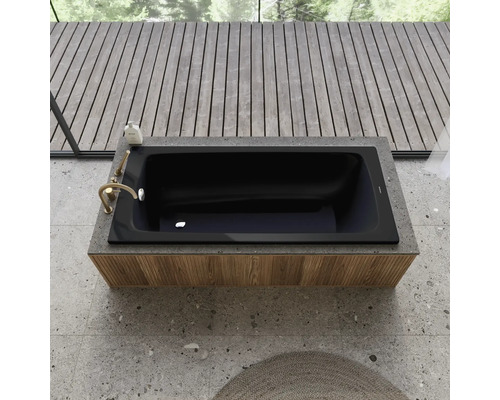 Baignoire noire encastrée dans une étagère avec robinetterie et produit de bain, entourée d''un plancher en bois