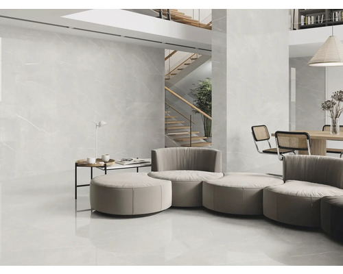 Heller Wohnraum mit grossformatigen Fliesen an Boden und Wand, Treppe im Hintergrund
