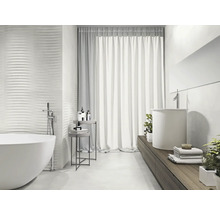 Salle de bain lumineuse avec baignoire îlot, lavabo et carreaux muraux structurés pour un design moderne.