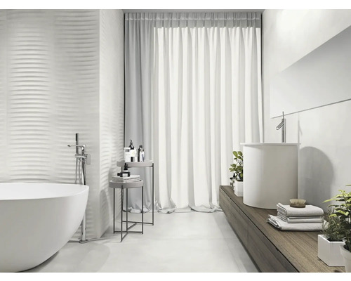 Salle de bain lumineuse avec baignoire îlot, lavabo et carreaux muraux structurés pour un design moderne.