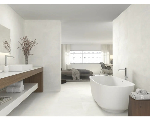 Salle de bains lumineuse avec baignoire, lavabo et accès à la chambre