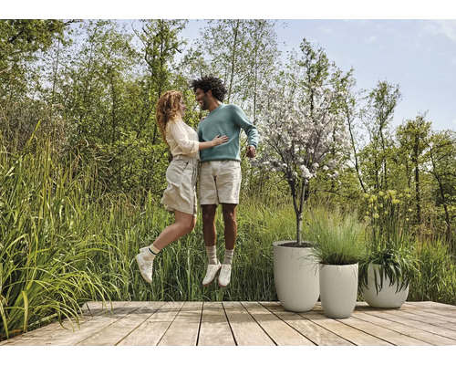 Szene mit Paar auf Holzterrasse neben strukturierten Pflanzgefäßen und Garten
